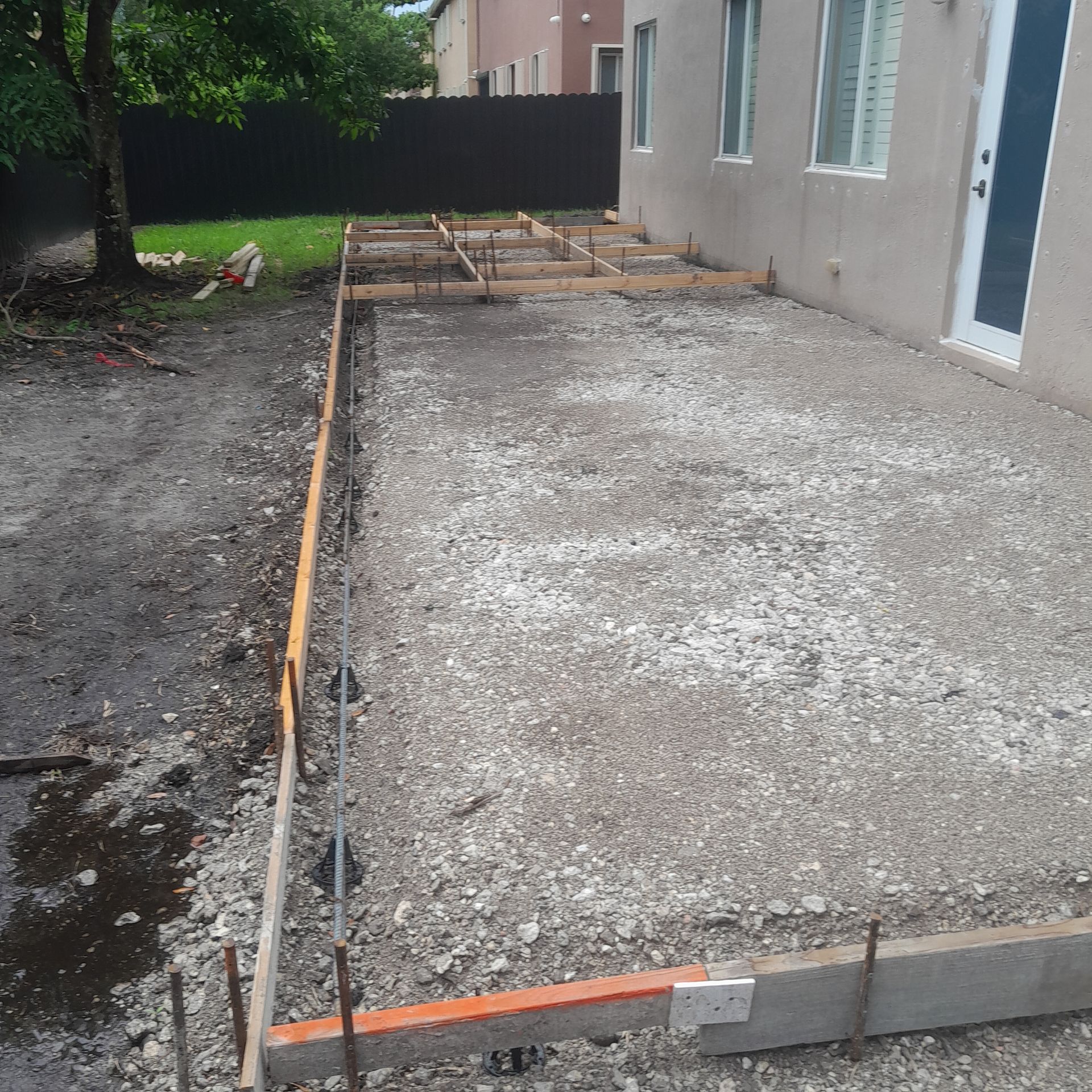 Concrete patio construction in progress; gravel base, wooden forms, rebar visible in Parkland FL