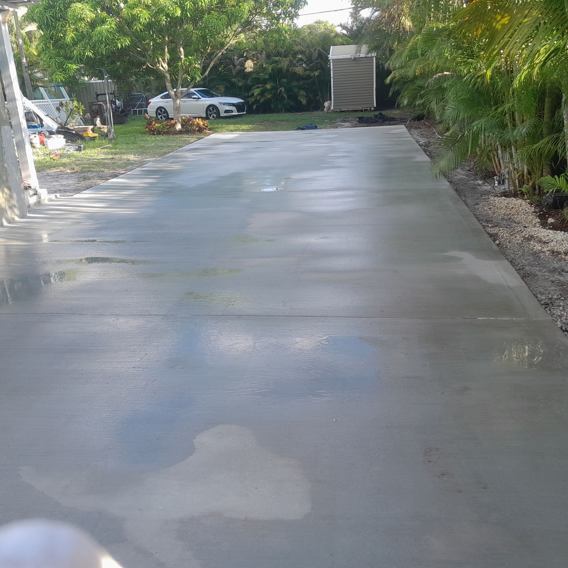 Newly poured concrete driveway, wet and reflecting light in Parkland FL