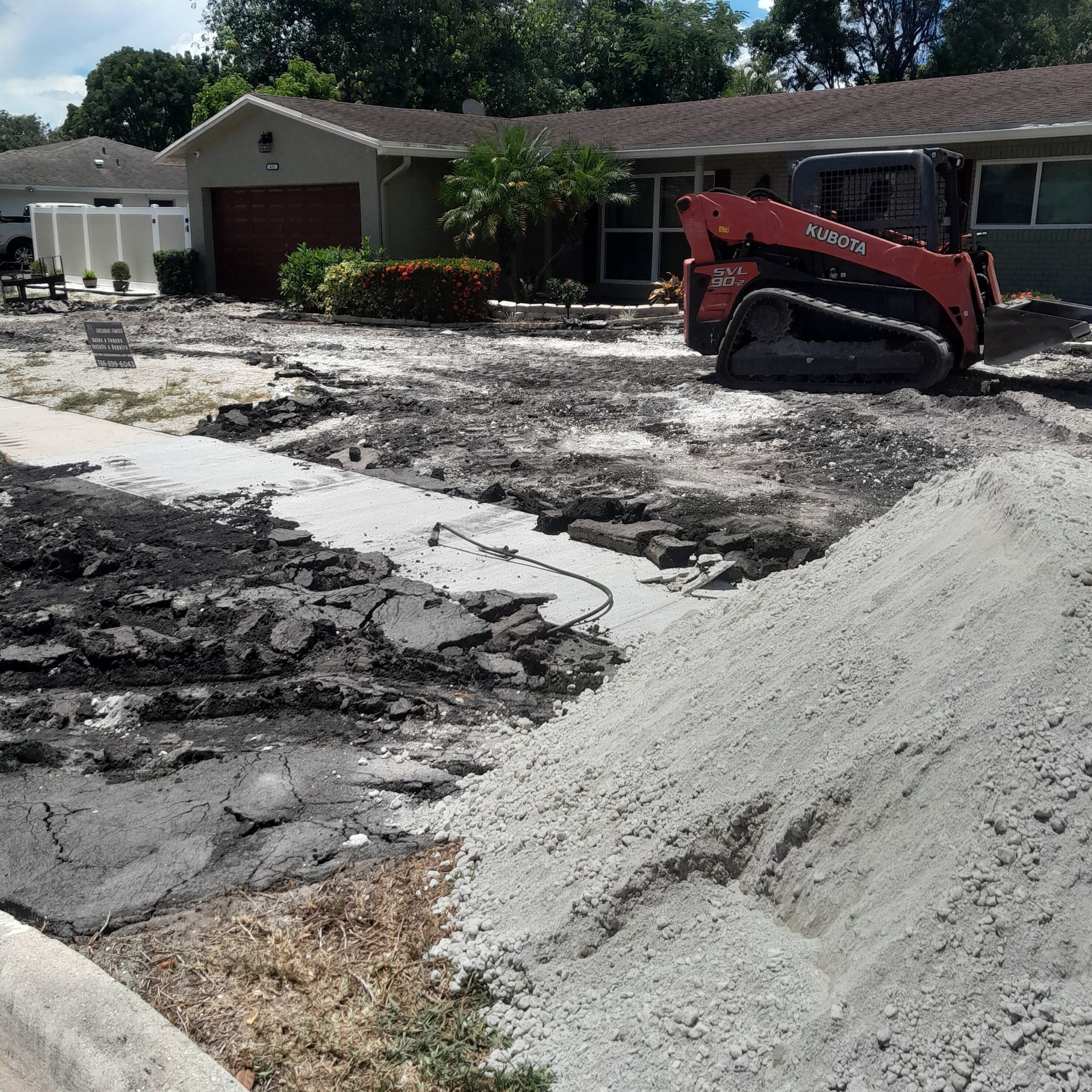 A red Kubota skid steer works on a yard in Parkland FL