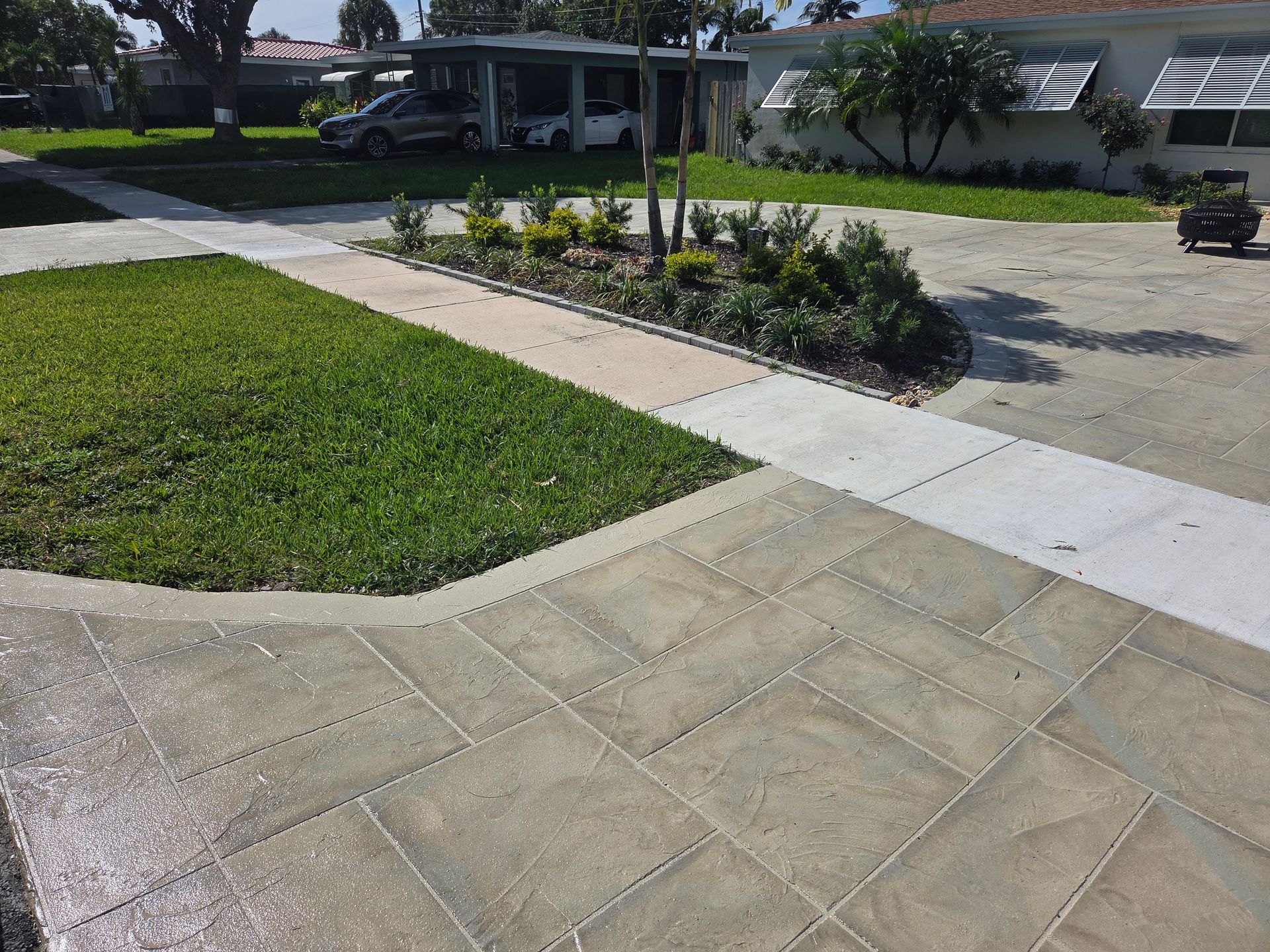 Concrete driveway and sidewalk with grass and small garden in Parkland FL