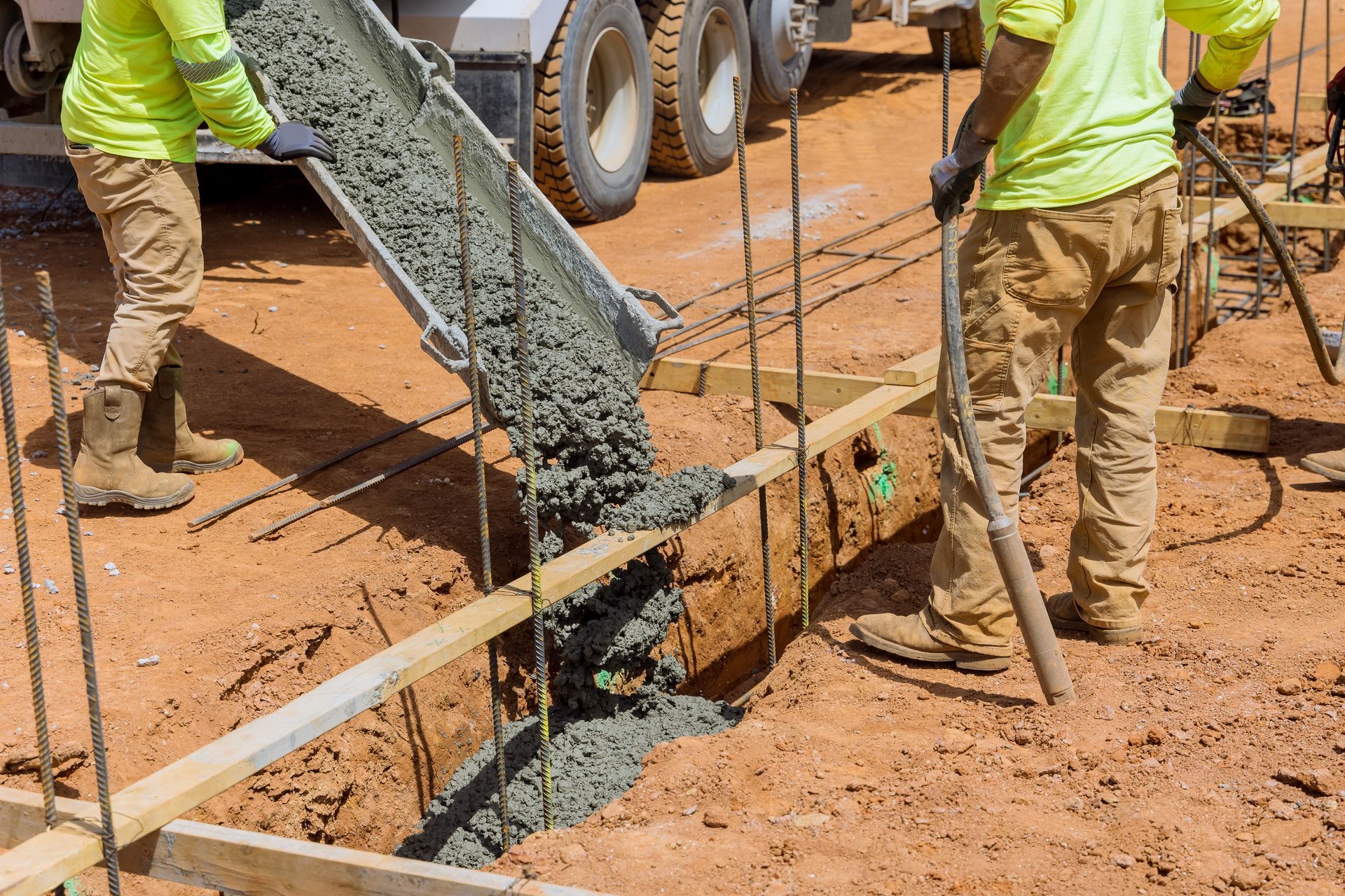 A group of construction workers are pouring concrete into a hole.