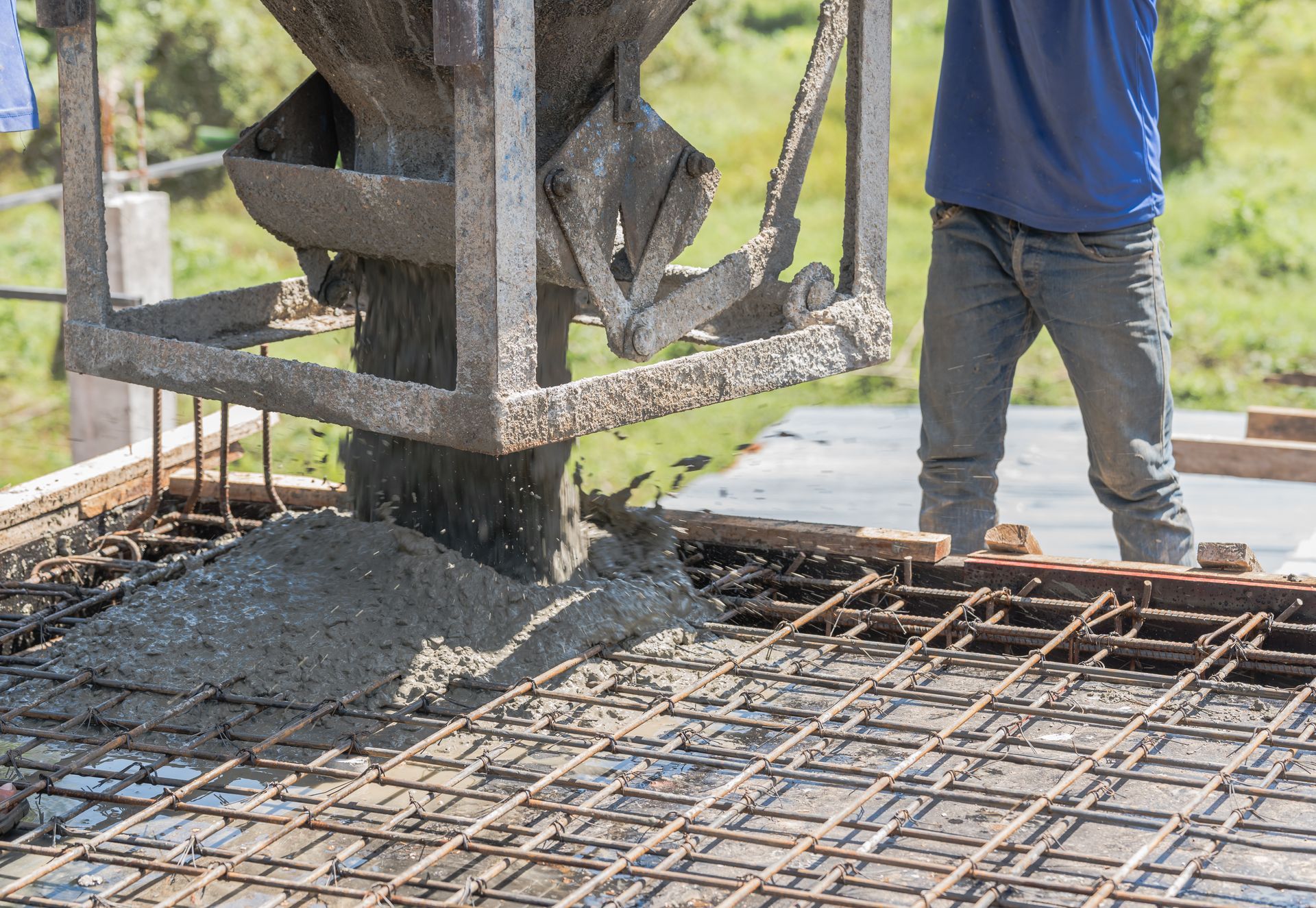 A man is pouring concrete into a concrete slab on a construction site.