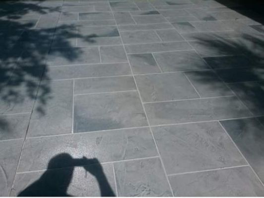 A person is taking a picture of their shadow on a tiled floor.