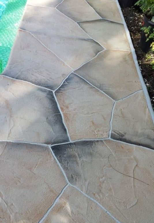 A close up of a stone walkway next to a pool.