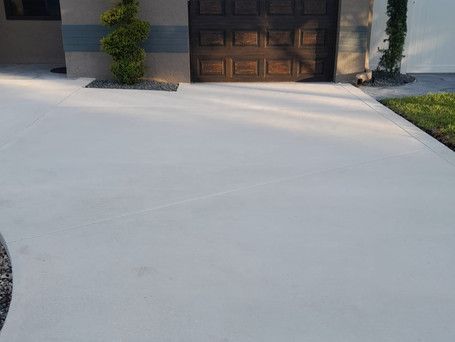 A concrete driveway in front of a house with a garage door.