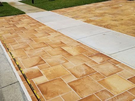 A sidewalk with brown tiles and a white walkway.