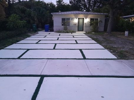 A white house with a concrete driveway in front of it