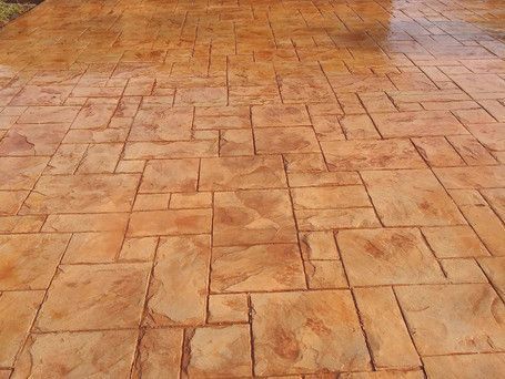 Affordable stamped concrete driveway with a cobblestone pattern installed near a residential home.