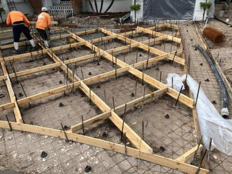 A group of construction workers are working on a concrete floor.