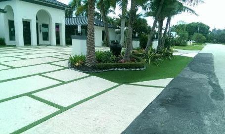 A white house with a large driveway and a palm tree in front of it