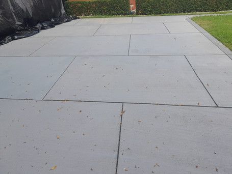 A concrete walkway with a black tarp on the side of it.