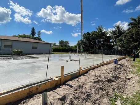A concrete slab is being poured in front of a house