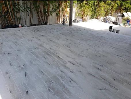 A white wooden floor with a few trees in the background.