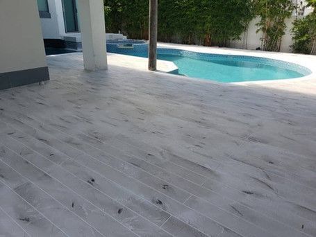 A wooden deck with a swimming pool in the background.