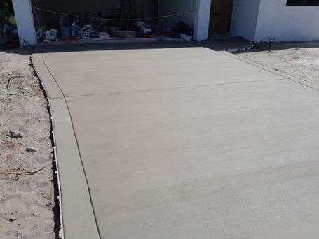 A concrete driveway is being built in front of a garage.