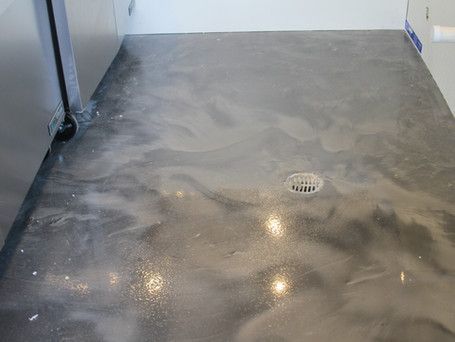 A gray concrete floor with a drain hole in the middle of it.