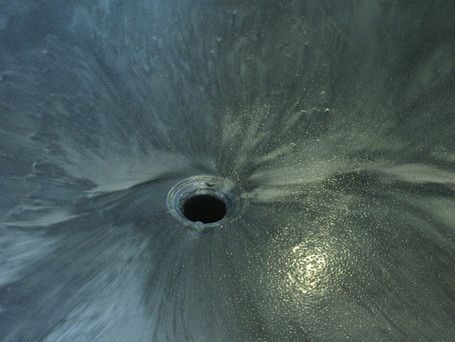 A close up of a sink drain with water coming out of it.