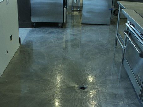 A kitchen with stainless steel appliances and a concrete floor