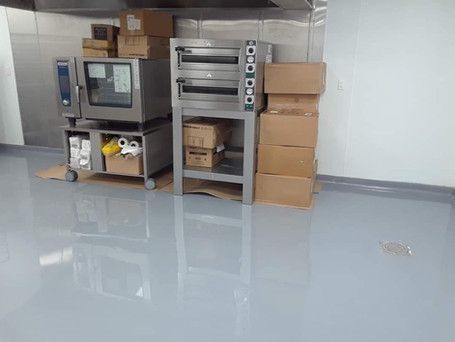 A kitchen with a stainless steel oven and boxes on the floor.
