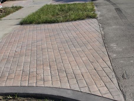 A sidewalk with bricks and grass on the side of it