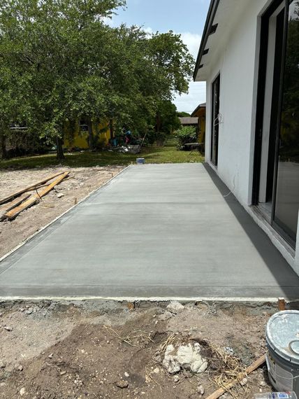 A concrete driveway is being built in front of a house.