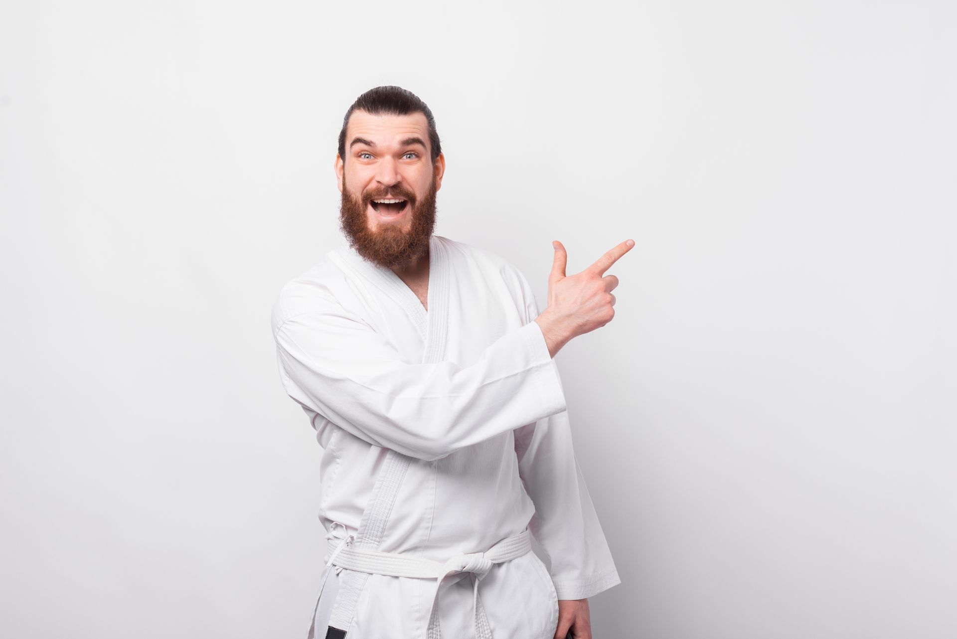 a man in a white karate uniform is pointing to the side .