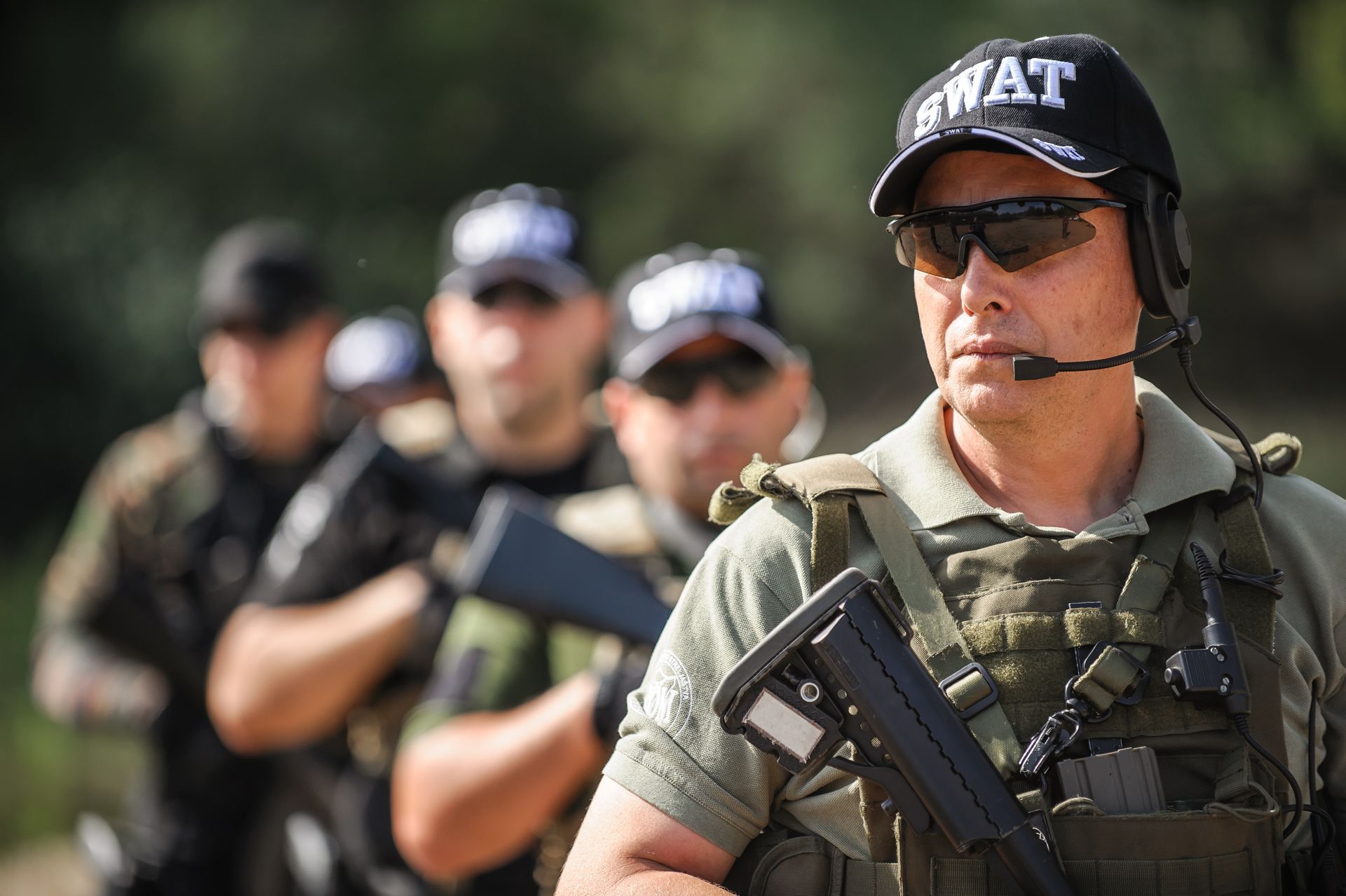 A man in a swat hat is standing in front of a group of soldiers.