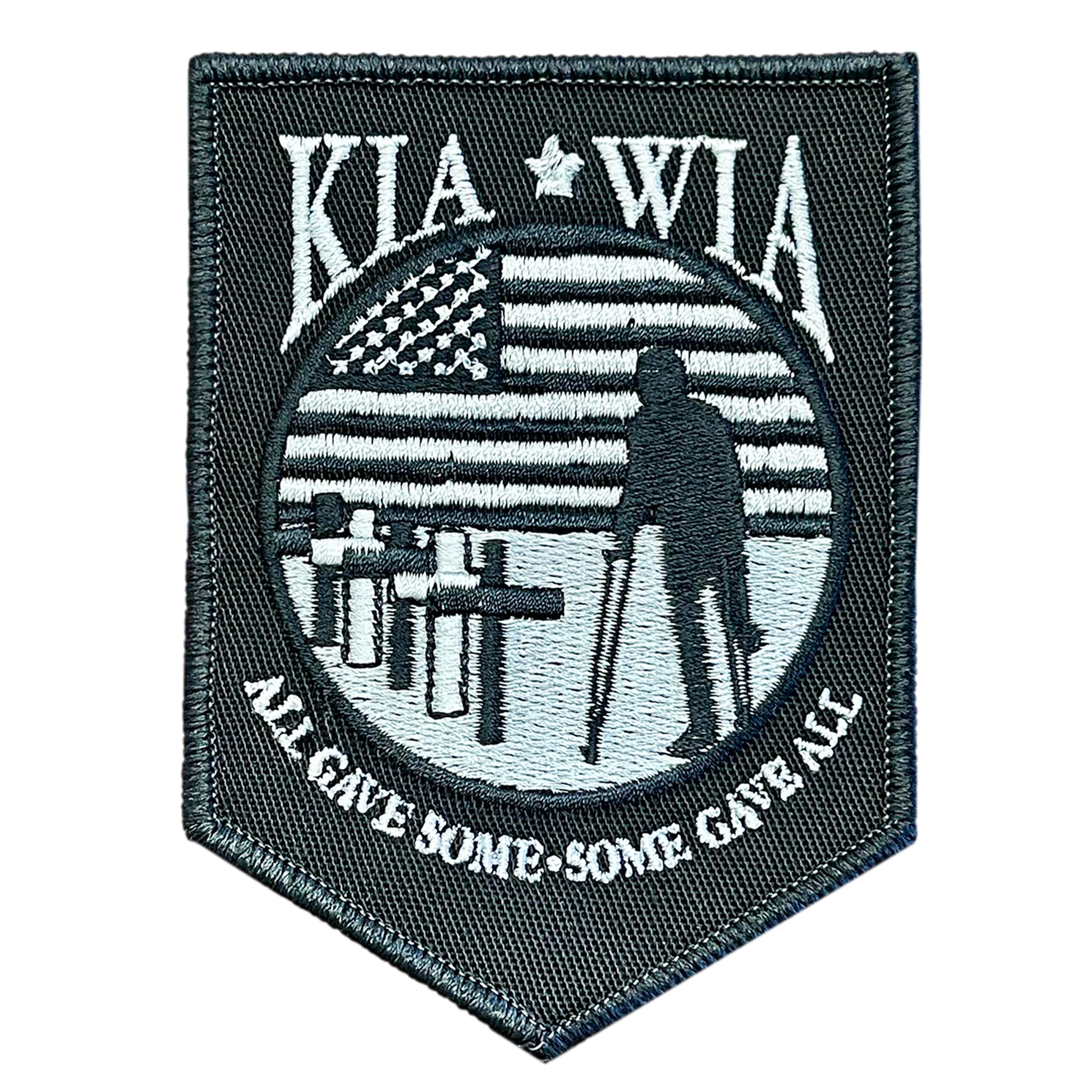 A patch with an american flag and a soldier standing in front of a cross.