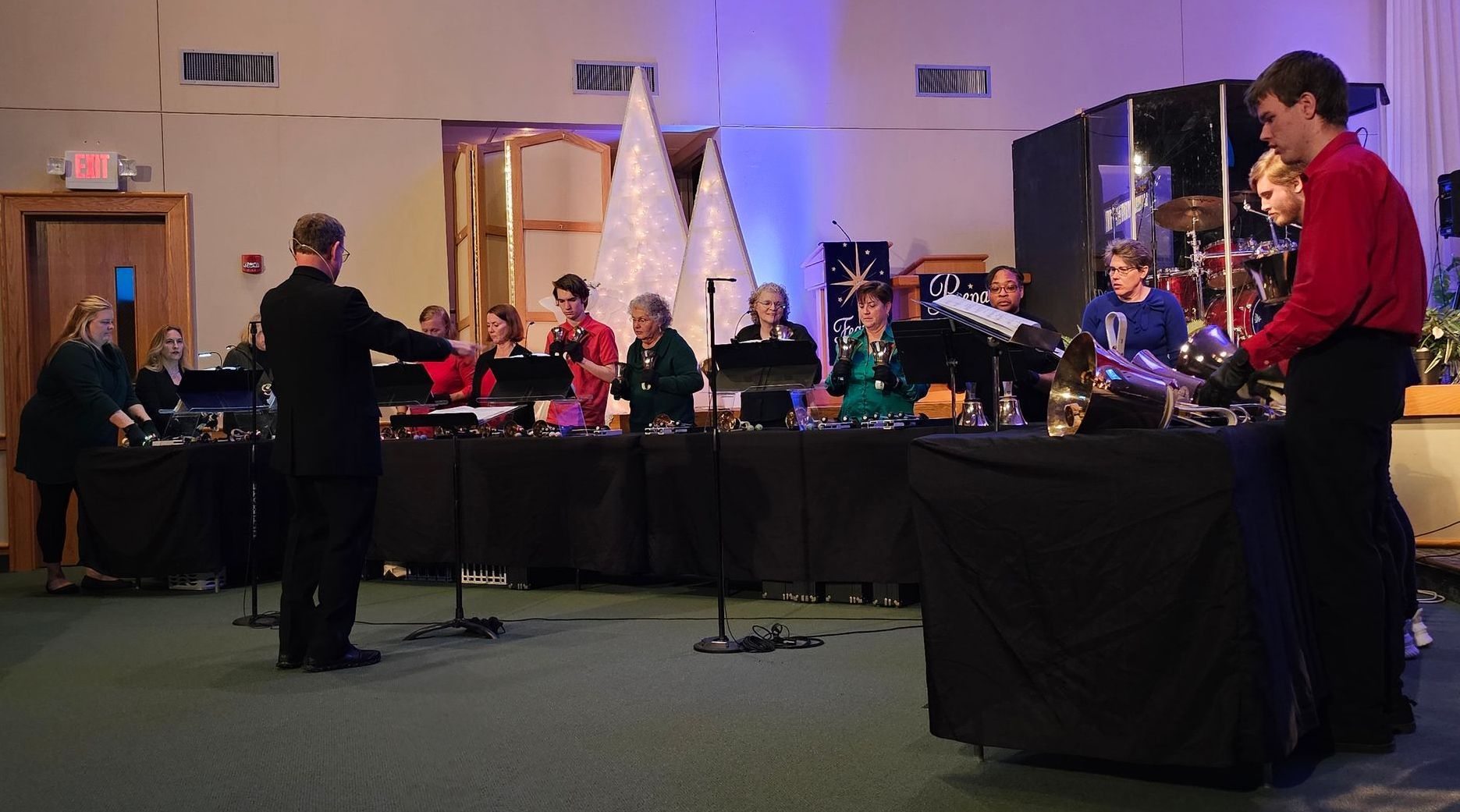 A man in a red shirt is standing in front of a band