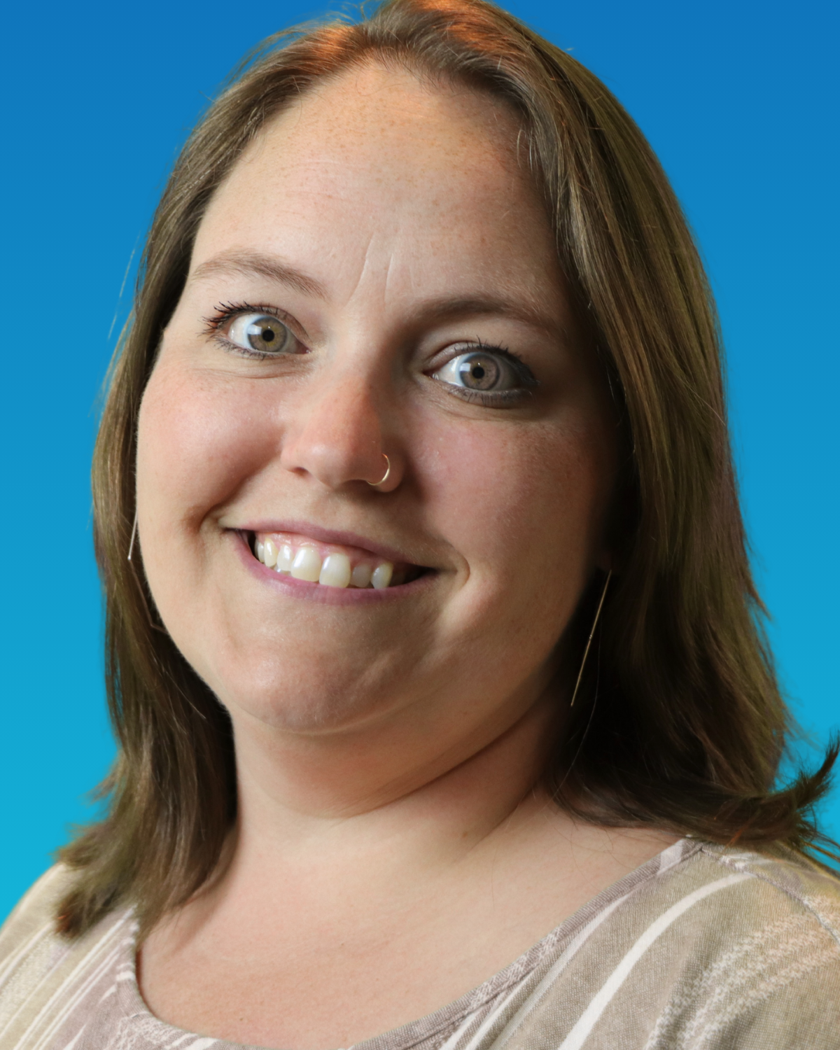 A woman is smiling and wearing a white shirt with flowers on it
