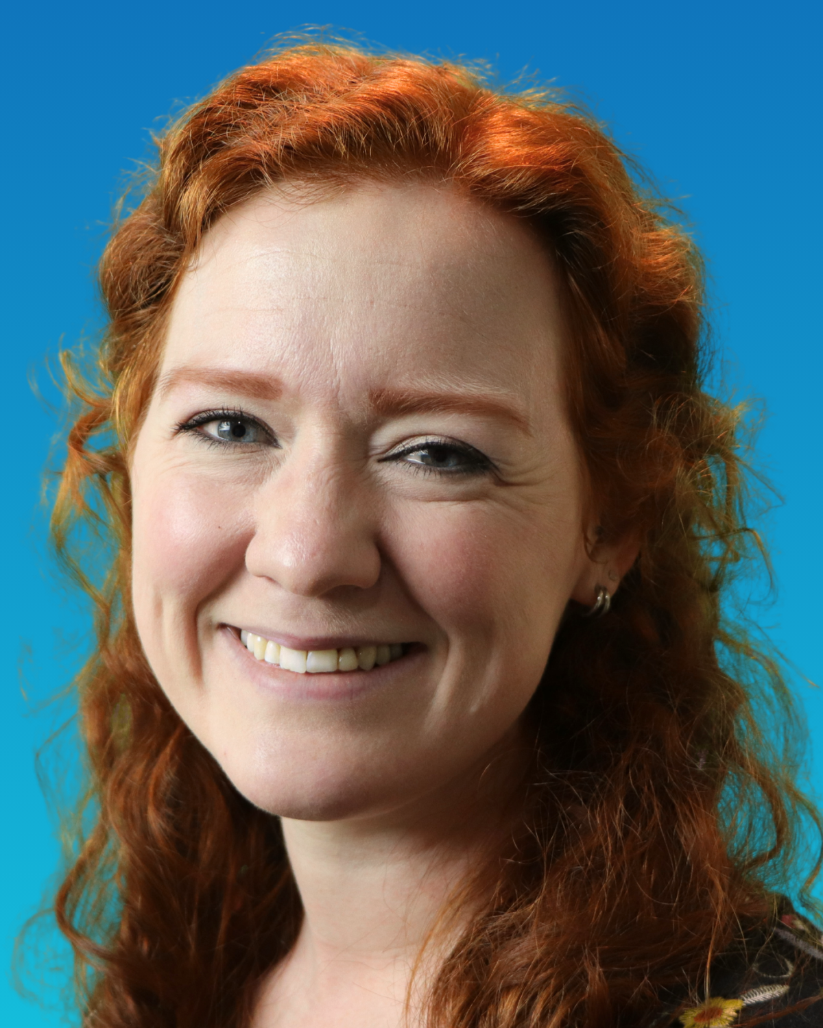 A woman with red hair is wearing a black shirt and smiling.