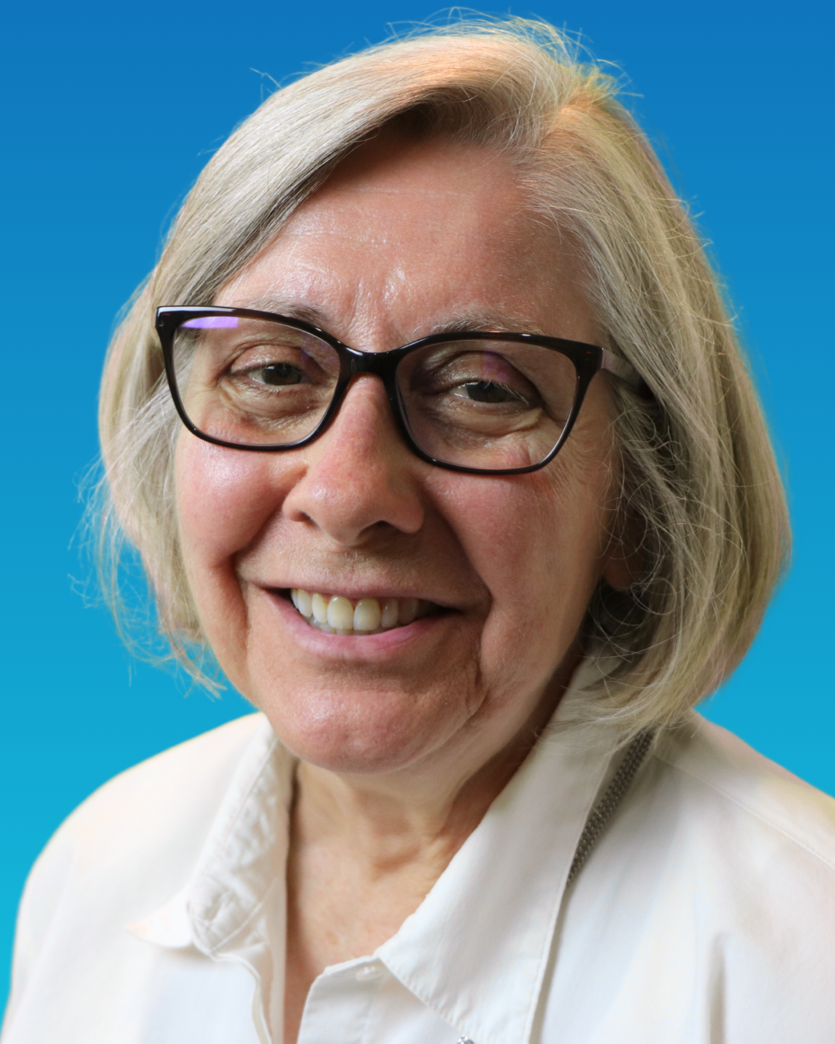 A woman wearing glasses and a purple sweater is smiling