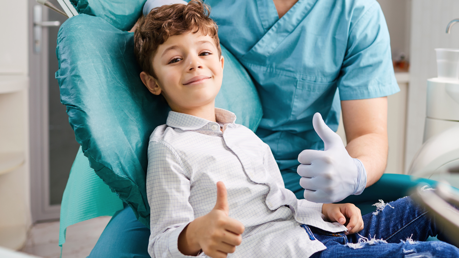 Boy and dentist giving thumbs up in dental chair.