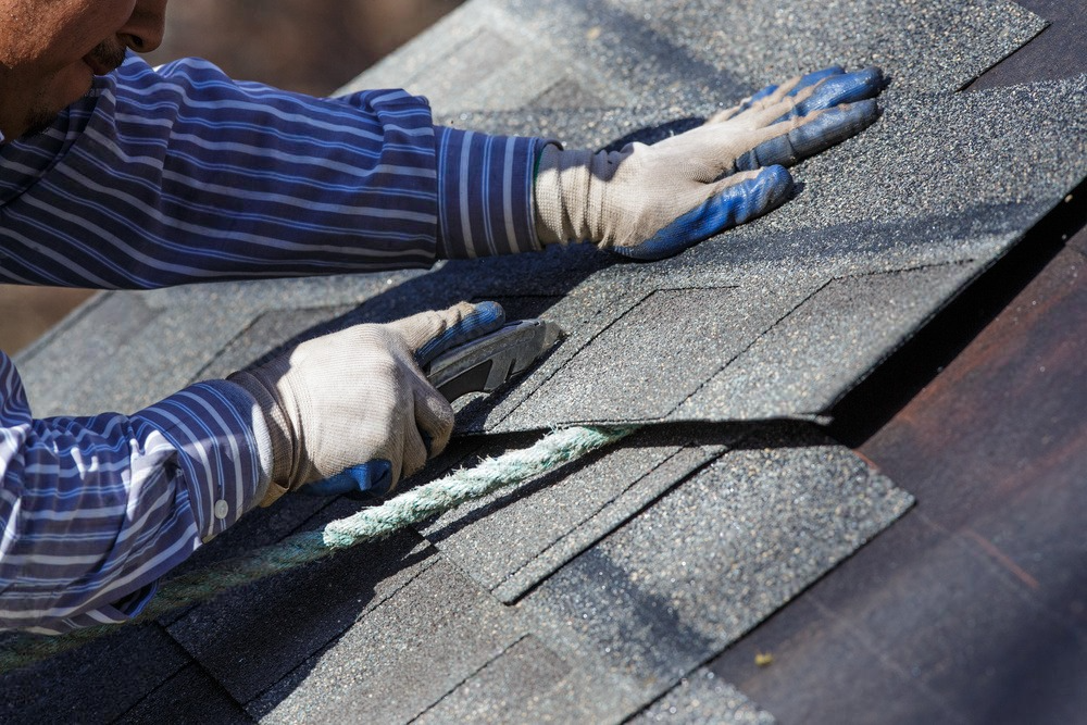 A man is working on a roof with a pair of pliers.