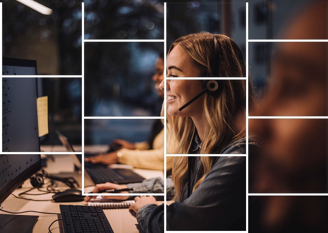 A woman wearing a headset is sitting at a desk in front of a computer.