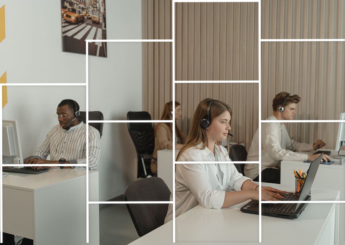 A group of people are sitting at desks in an office working on laptops.