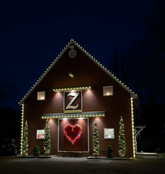Red barn at night, decorated with lights, a heart, and the letter 
