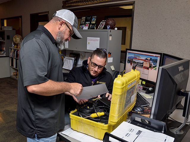 Two men are working on a yellow case in an office.