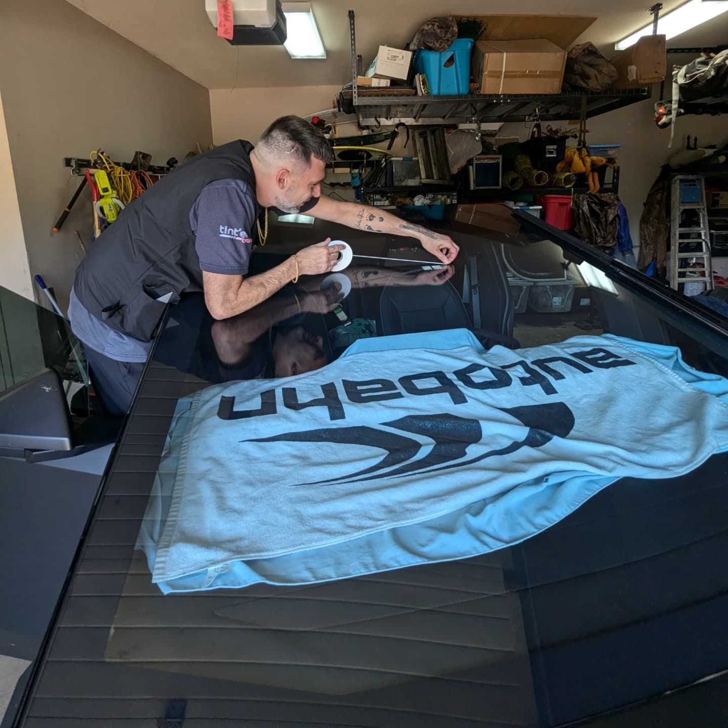 A man is cleaning the windshield of a car in a garage.