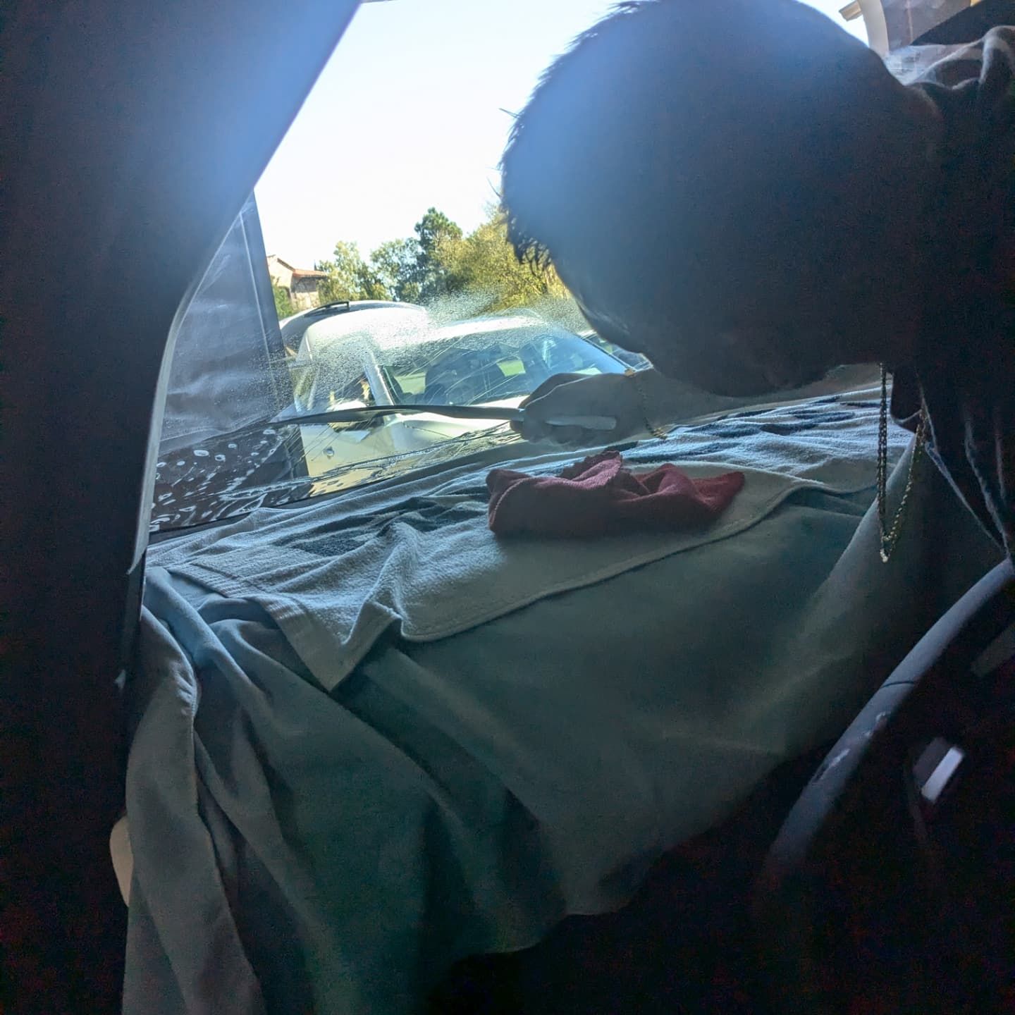 A man is cleaning the windshield of a car with a cloth