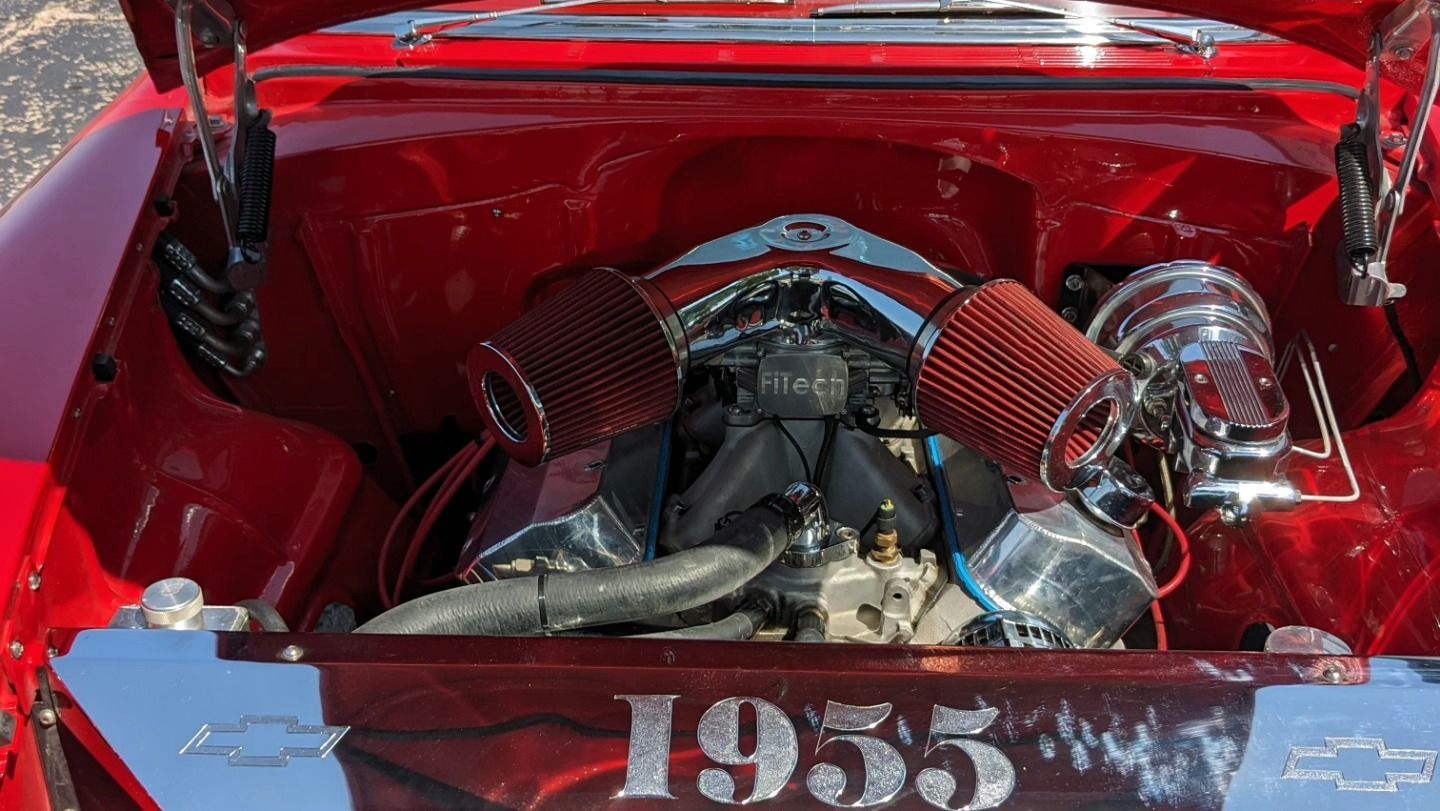 A red car with the hood up and the engine visible.