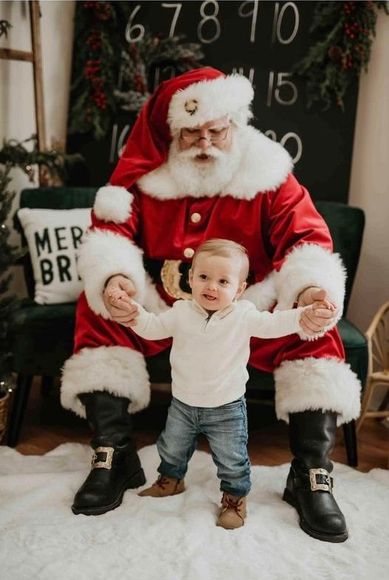 Santa Claus with two children, red sweaters, Christmas tree, poinsettias, window.