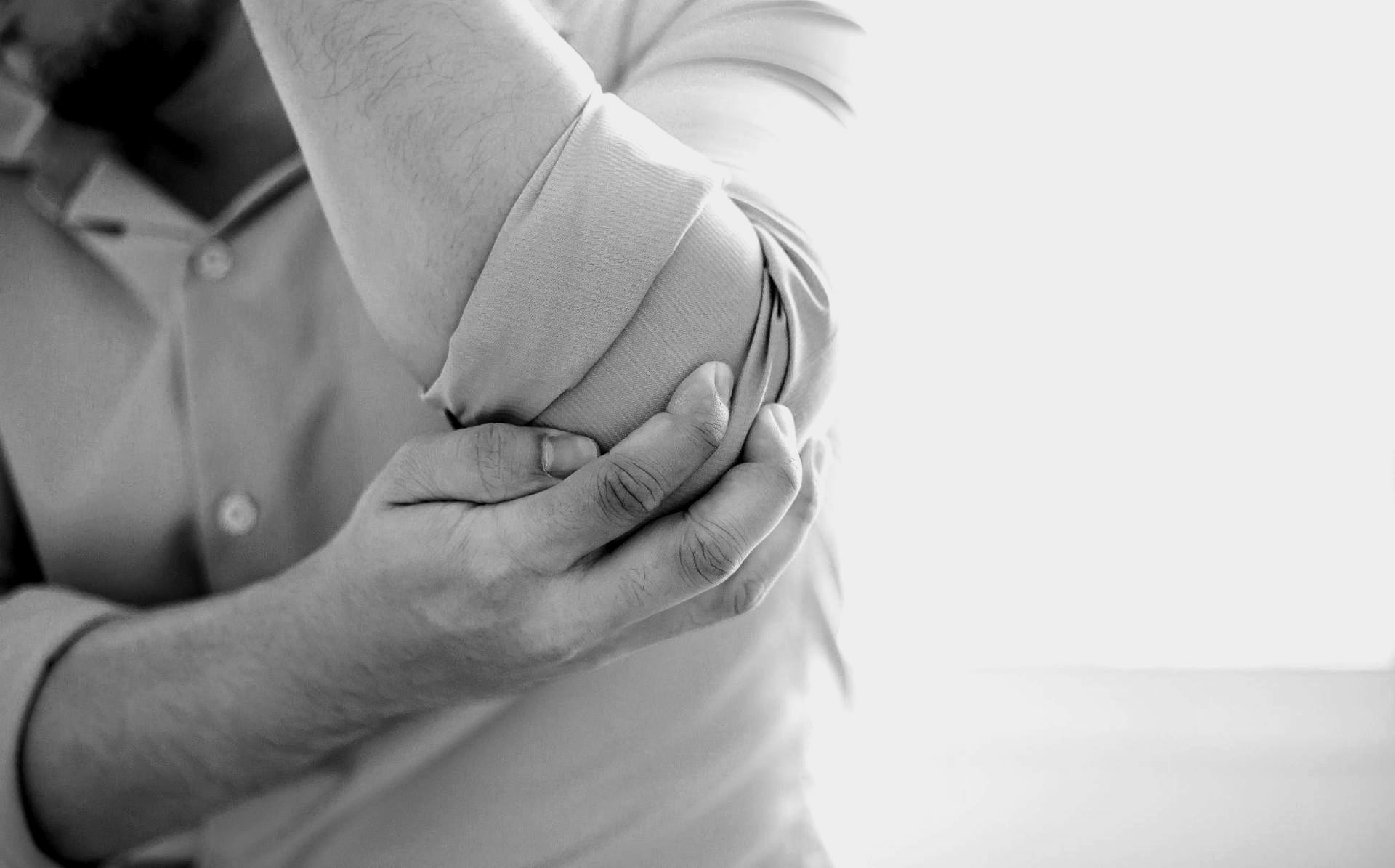 black and white closeup photo of person holding painful elbow with cubital tunnel syndrome