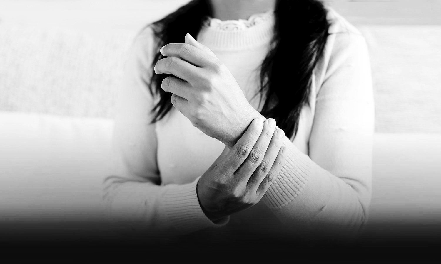 black and white photo of a woman with black long hair holding injured wrist