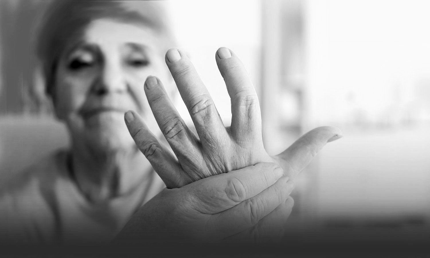 black and white photo of an elderly woman holding her painful hand