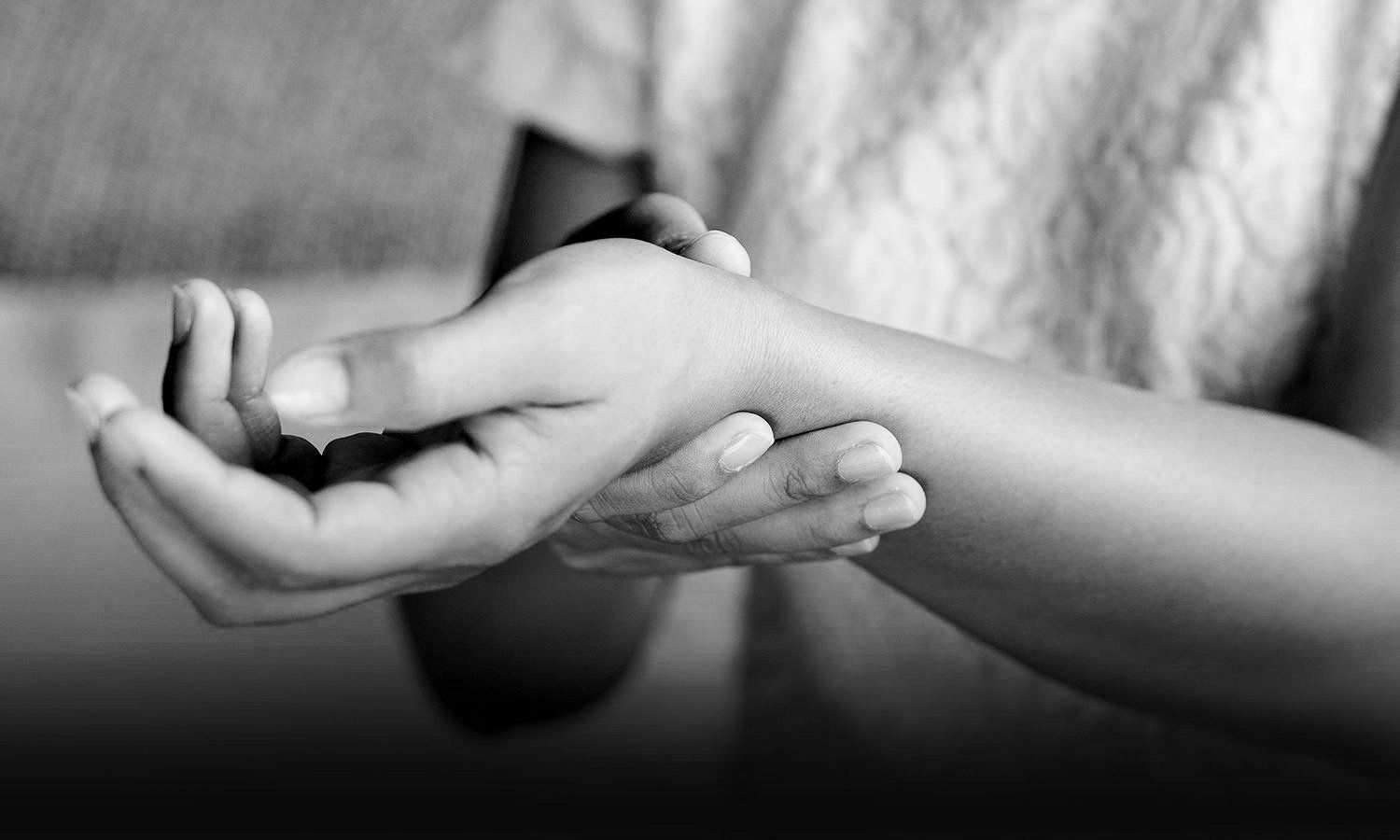 black and white closeup photo of person holding injured wrist from carpal tunnel syndrome