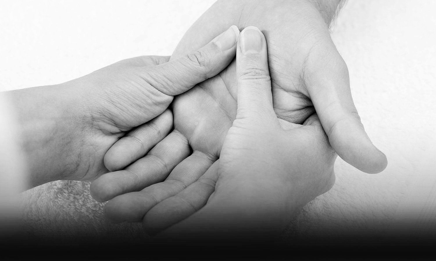 black and white closeup photo of physical therapist massaging patient's painful hand