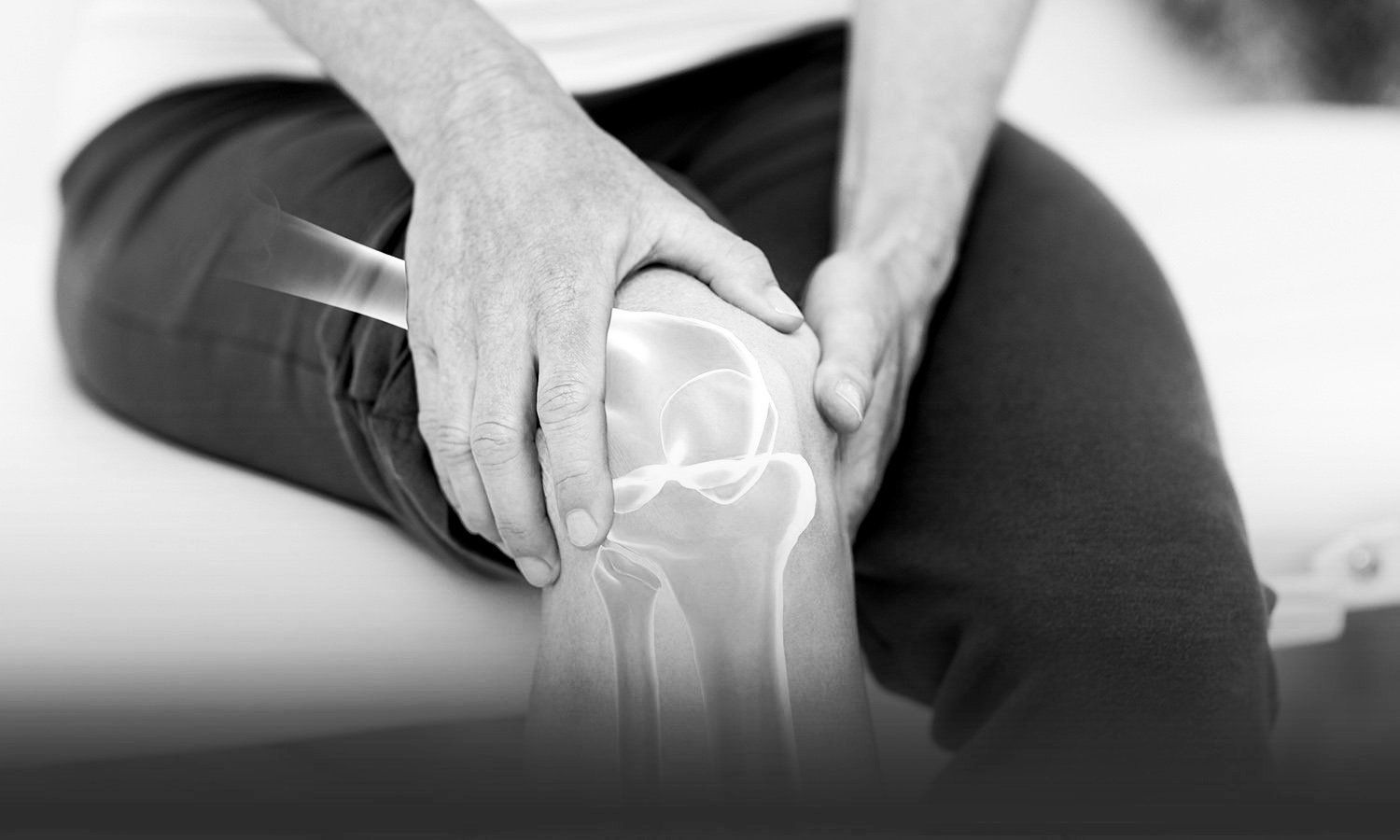 black and white closeup photo of someone holding knees with both hands. knees is showing illustration of bones