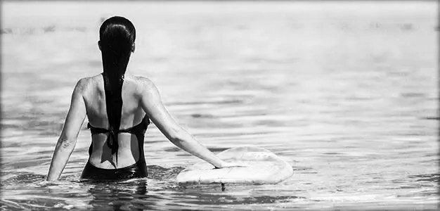 rear view of woman in ocean with surfboard