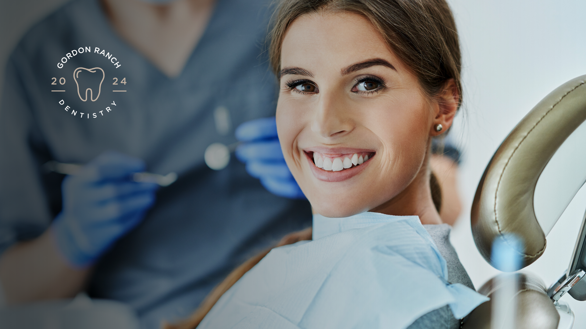 A woman is smiling while sitting in a dental chair.